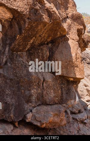 Close-up of rugged, weathered brown rock formations with uneven textures and natural sunlight highlighting the surface details. Stock Photo