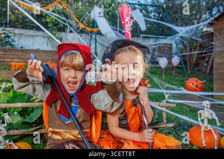 Two kids dressed in Halloween costumes scream, make scary faces Stock Photo