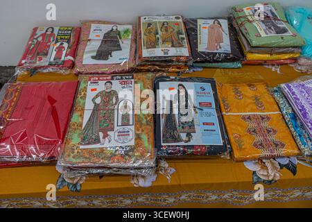 Beautiful traditional printed dresses neatly packaged and arranged on bright patterned tablecloth Stock Photo