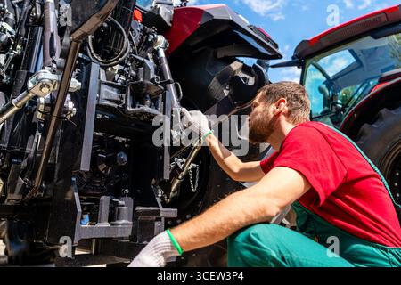 Agricultural machinery mechanic checking farm tractor Stock Photo