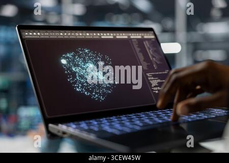 Close up of data center technician using laptop, running AI forecasting simulations, tracking performance. Server hub IT specialist uses notebook to integrate artificial intelligence API into software Stock Photo