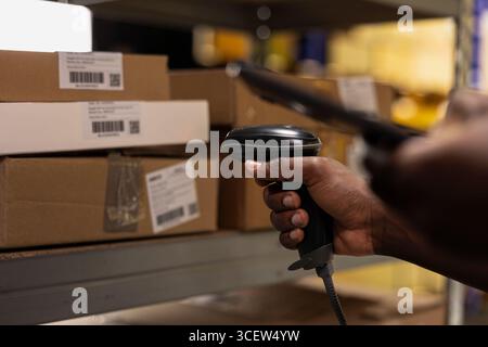 Black staff member using a barcode scanner to process shipping labels ...