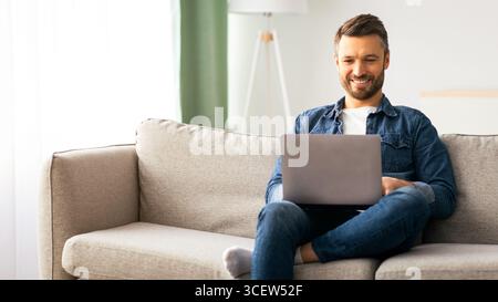 Handsome bearded man using laptop and smiling Stock Photo