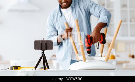 Handyman blogger shooting video instructions for assembling furniture at home with own hands, using electric drill, crop Stock Photo