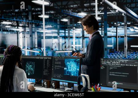 Data center developer monitoring AI systems, adjusting machine learning parameters. Server hub IT employee in office enhancing artificial intelligence software performance Stock Photo