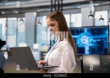 Junior dev in office using AI automation scripts to reduce repetitive coding tasks. Young female software developer using artificial intelligence technology in startup workspace Stock Photo