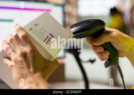 Close up of worker manages cargo barcode scanning in a distribution hub, preparing the goods with packaging, tagging and inventory checking. Man using a scanner in fulfillment center. Stock Photo