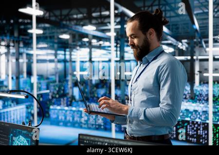 Programmer working in server farm with hardware supporting advanced analytics tasks and data mining. Data center IT expert doing maintenance on racks storing blockchain records Stock Photo