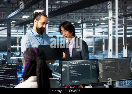 Server farm IT employees deploying AI tools to automate repetitive workflows. Data center software developers managing large datasets used in AI training procedures to streamline tasks Stock Photo