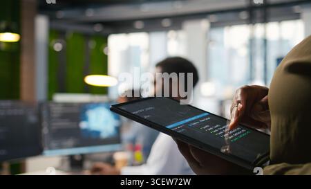 Close up of programmer utilizing AI on tablet to optimize performance and forecast issues. System administrator in office training machine learning models using device, camera A Stock Photo