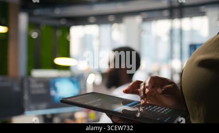 Close up of engineer using tablet to write code, developing machine learning APIs. IT professional troubleshooting software errors and faults using artificial intelligence, camera A Stock Photo