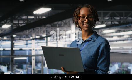 Portrait of joyful computer scientist in data center monitoring neural network LLM visualization. Upbeat woman in server farm overseeing rigs powering machine learning processes Stock Photo