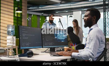System administrator in office using PC, automating repetitive tasks with AI scripts. IT specialist using artificial intelligence technology to speed up feature implementation, camera A Stock Photo
