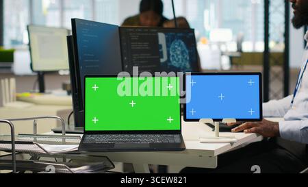Software developer using AI on isolated screen laptop and tablet to optimize performance and forecast issues. IT expert in office training machine learning models using chroma key notebook, camera A Stock Photo