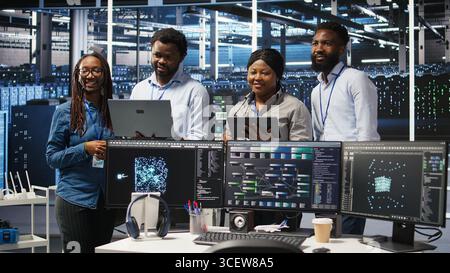 Smiling server hub engineers collaborating, using AI algorithms and node tree systems to categorize unstructured data. Colleagues use visual programming and natural language processing tools, camera A Stock Photo