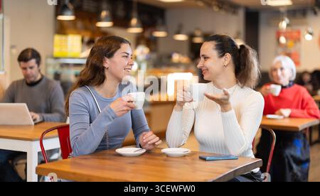 Woman in cafe sits near girl companion, has nice conversation Stock Photo
