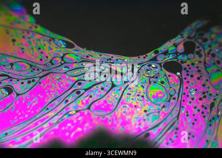 Kaleidoscopic montage of patterns on a soap bubble showing light interference patterns. The pattern and colours on the surface of the bubble are caused by light reflecting from both the front and back of the soap film. The thickness of the film varies across the surface of the bubble, affecting the wavelength of incident white light. Certain wavelengths of white light are extinguished, producing the colour interference pattern seen here. Stock Photo