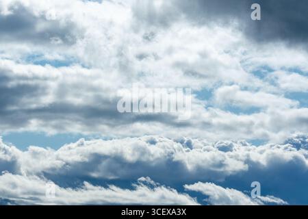 Cumulus and Stratus Clouds Layered in Dramatic Blue Sky with Light and Shadows. Stock Photo