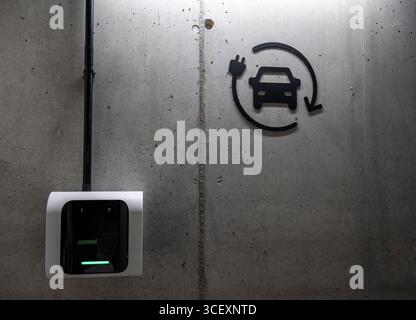 A black and white sign with a car on it and a green light. The sign is on a wall Stock Photo
