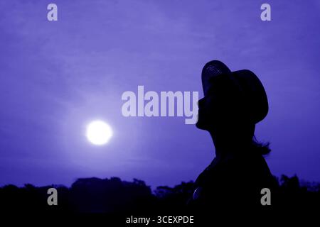 Pop art surreal style of silhouette of a woman looking up to bright sun sky in blue tone Stock Photo
