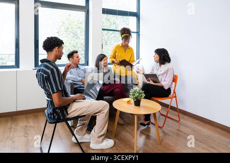 Five business professionals engaged in a productive meeting within a modern office, collaborating and brainstorming strategies to achieve shared goals Stock Photo