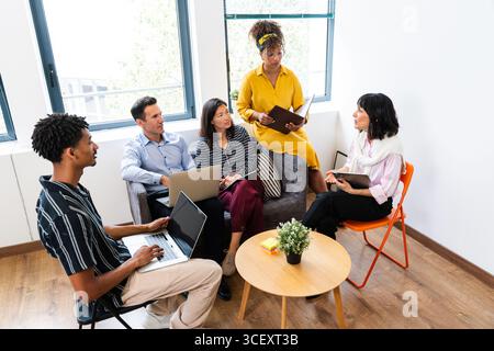 Multi-ethnic business team collaborating during a productive meeting in a modern office space, utilizing laptops and sharing ideas for successful proj Stock Photo