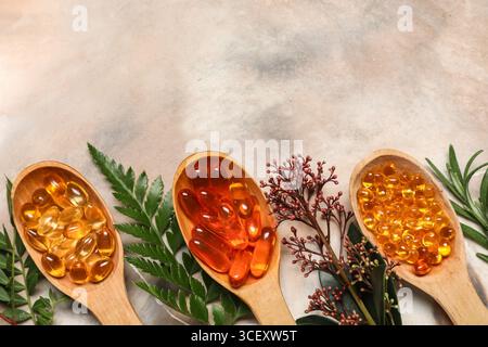 Wooden spoons with different pills and fresh plants on grunge background, closeup Stock Photo