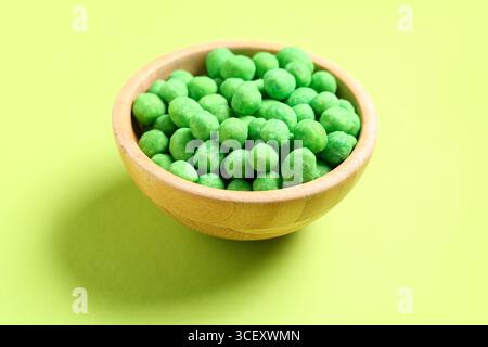 Bowl with wasabi coated peanuts on green background Stock Photo
