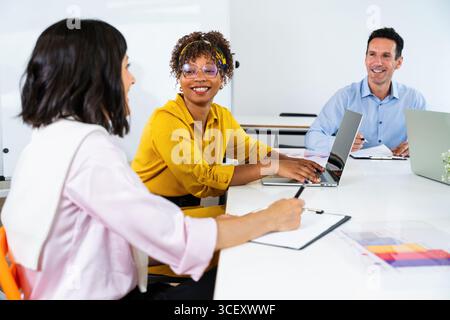 Startup business team discussing new project during a meeting sitting at table in modern office space, analyzing financial statistics displayed on the Stock Photo