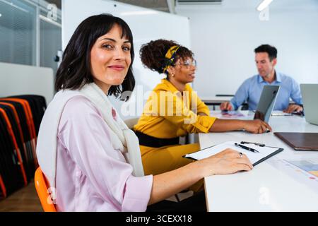 Business team collaborating on project during meeting in modern office, using laptops and taking notes, showcasing teamwork and productivity in profes Stock Photo