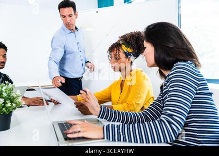 Business colleagues collaborating on a project, analyzing documents, and discussing strategies during a productive meeting in a modern office environm Stock Photo