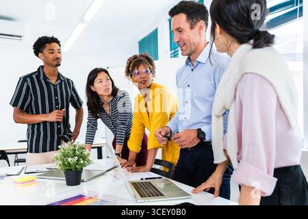 Diverse team of professionals working together, analyzing data and discussing strategies during a productive meeting in a modern startup office enviro Stock Photo
