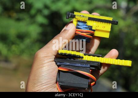 Small and medium sized servo with its shaft connected to 3d printed slider mechanisms held in the hand. Servos for robotic projects Stock Photo