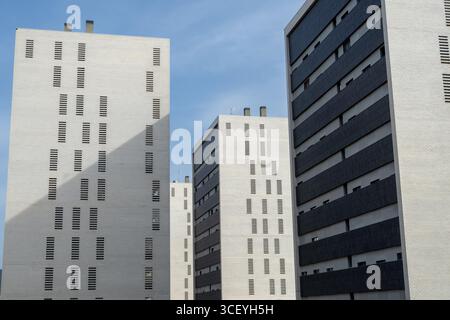 Low angle view of modern residential buildings with repeating patterns and contrasting colors under a clear blue sky Stock Photo