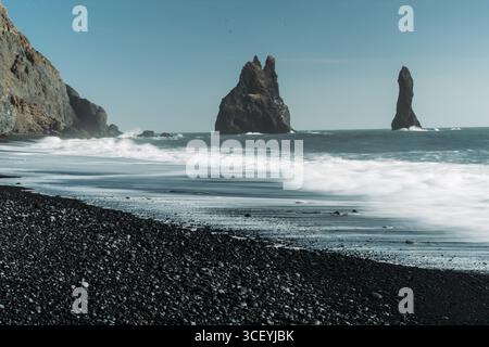 Dramatic black sand beaches and sea stacks at Reynisfjara, alongside a ...
