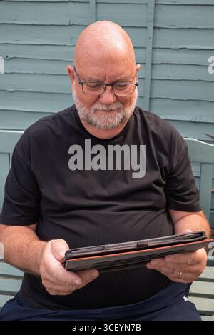 Senior man using a tablet outdoors. Staying connected and informed. Old people and technology. Stock Photo