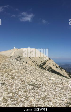 Wide view of Mont Ventoux rocky summit in Provence France with the famous white tower against deep blue sky and vast mountain landscape Stock Photo