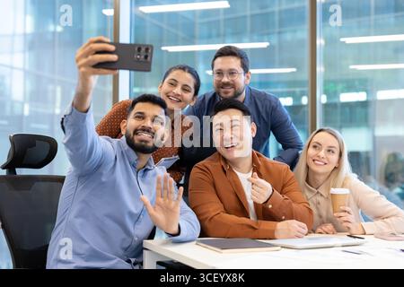 A diverse team of colleagues taking a selfie together, showcasing teamwork, unity, and positivity in a dynamic workplace environment. Stock Photo