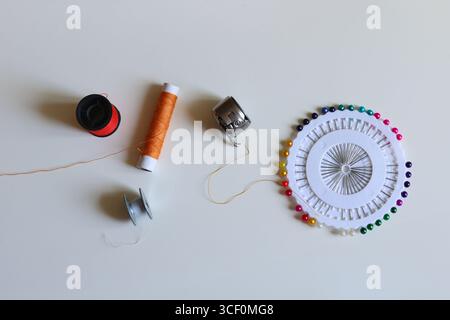 Tailoring supplies on fabric background spools, needle, and bobbin for creative work Stock Photo