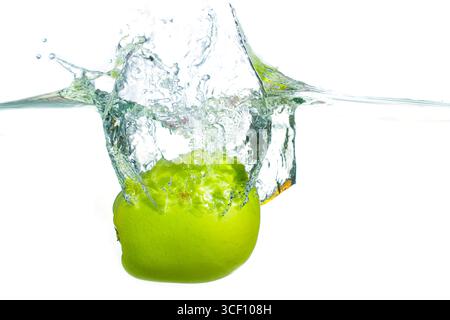 Dynamic splash of water created by a green apple dropping into clear liquid, frozen in time, highlighting the fruit's vibrant color and movement. Stock Photo