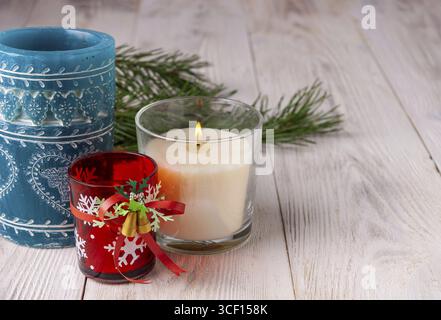 Candles in glass jars stand on a light wooden background Stock Photo