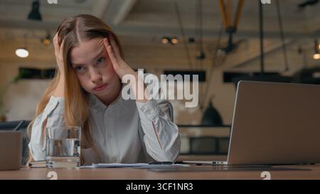 Frustrated Caucasian office female manager business woman girl review documents paperwork difficult job writing report businesswoman stack feeling Stock Photo