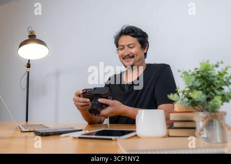 A young male photographer working from home, editing photos on a computer with creative software in a cozy workspace Stock Photo