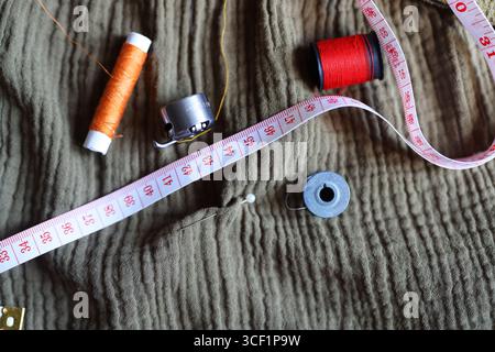 Sewing accessories on fabric, colorful threads, needle, bobbin, and pin for tailoring. Stock Photo