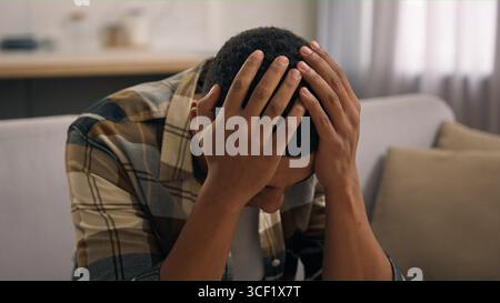 Upset sad disappointed African American male guy man failure with online betting casino lost money at home reading bad news problem trouble with Stock Photo