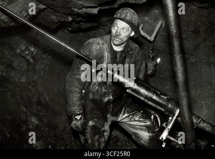 Iron ore mining in Kiruna, Sweden/Lapland, 1940. Large iron ore mines are being exploited through open-pit mining. The extracted ore is transported via the harbor in Narvik, located on the Atlantic Ocean. A miner operates a large drilling machine underground. Stock Photo