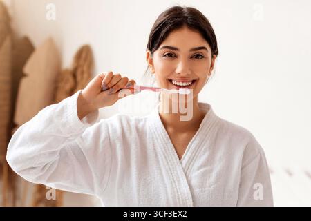 Woman Brushing Teeth With Toothbrush Smiling Standing In Bathroom Indoor Stock Photo