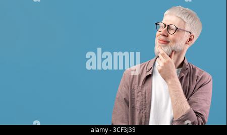 Pensive albino guy thinking over decision, looking at empty space over turquoise studio background Stock Photo
