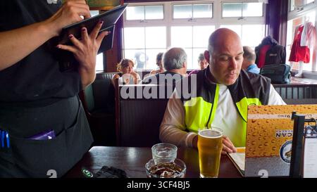 Waitress taking a lunch order from man looking at a menu, Pelican Pub & Brewery, Pacific City, Tillamook County, Oregon, USA Stock Photo
