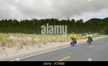 Two men riding fully loaded touring bicycles on tour of the Oregon coast. Sandlake, Tillamook County, Oregon, USA Stock Photo